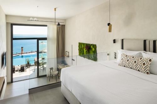 Schlafzimmer mit einem Bett und Meerblick in der Unterkunft Akrotiri Olympus Luxury Suites - Adults Only in Plaka