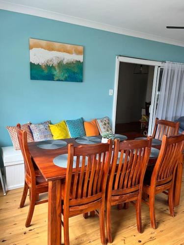a dining room with a table and chairs and a couch at My Cottage On Main in Boolaroo