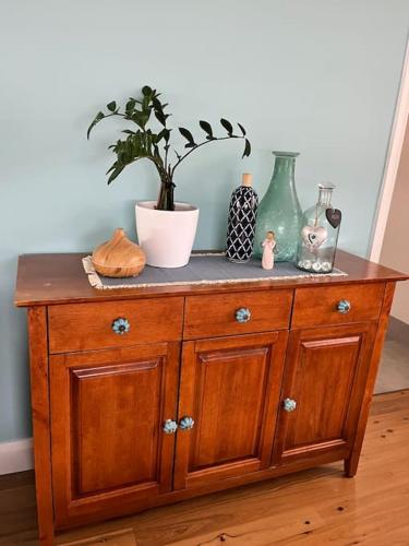 a wooden cabinet with vases and a plant on it at My Cottage On Main in Boolaroo