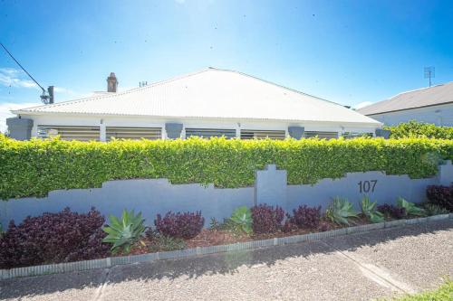 a house with a hedge in front of a building at My Cottage On Main in Boolaroo