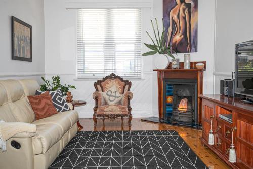 a living room with a couch and a fireplace at My Cottage On Main in Boolaroo