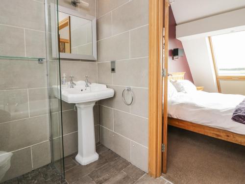 a bathroom with a sink and a shower and a bed at Primrose Cottage in Ulverston