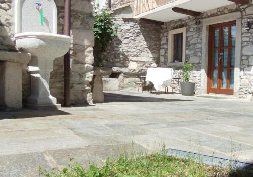 a stone house with a fountain in the courtyard at Casa Elisa affittacamere in Armeno