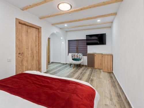 a bedroom with a red bed and a chair at Transylvania House in Arieşeni