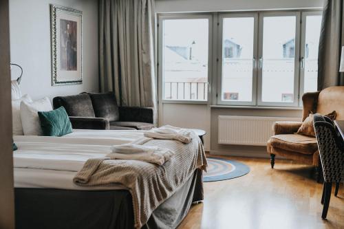 a bedroom with a bed and a couch and a window at Clarion Collection Hotel Majoren in Skövde