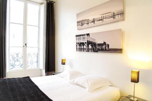 a bedroom with a bed and a picture of a pier at Condillac - Appartement 2 chambres avec ascenseur et Parking in Bordeaux