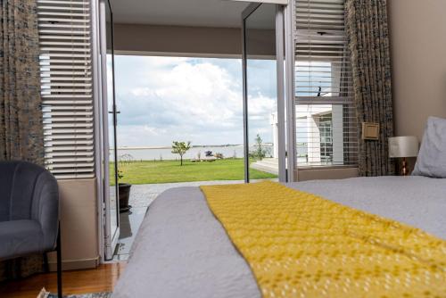a bedroom with a large window with a view of the ocean at 36 Emanzini (Holiday home lake view) in Denysville