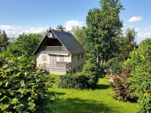 a house with a black roof on a green yard at Chata Mezičky in Jiřetín pod Jedlovou
