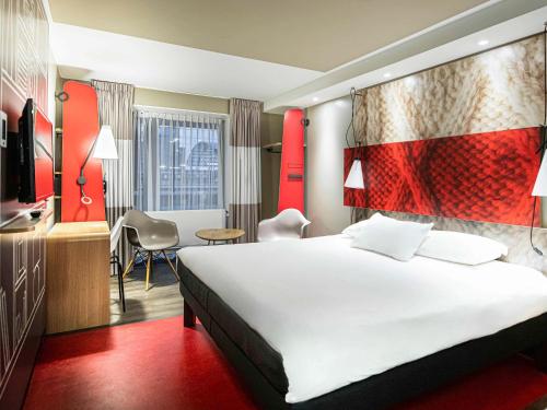 Pokój hotelowy z białym łóżkiem i czerwoną ścianą w obiekcie ibis Amsterdam Centre w Amsterdamie