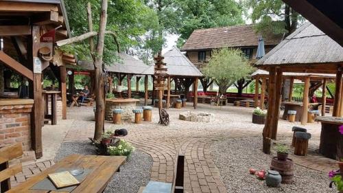 un patio con pabellones de madera, mesas y bancos en Etno Konačište-Restoran Stara Čivija en Bosanska Dubica