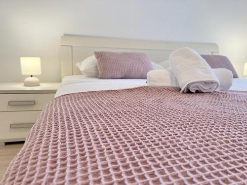 une chambre avec un grand lit avec une couverture rose dans l'établissement Palit Hills Superior Apartments, à Rab