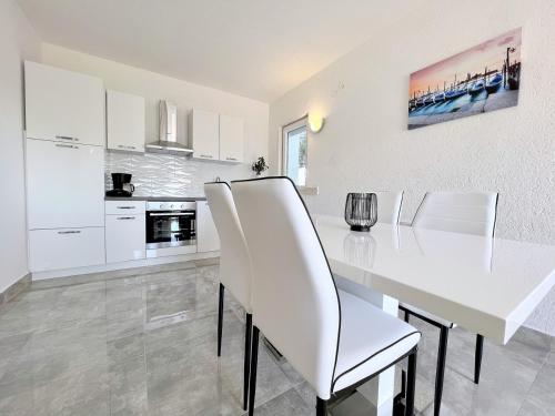 uma cozinha branca com uma mesa de jantar e cadeiras brancas em Palit Hills Superior Apartments em Rab