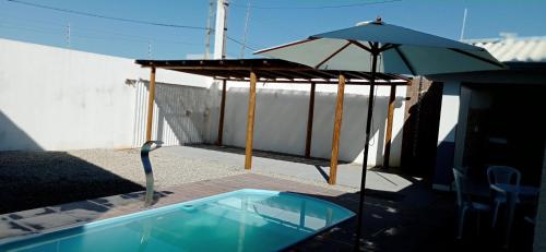 a swimming pool with an umbrella and a table and an umbrella at Casa com piscina e espaço gourmet a 30m da praia! in Alcobaça