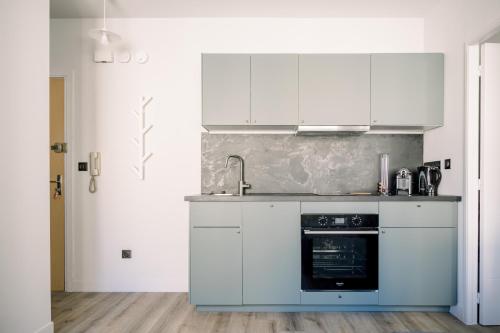 une cuisine avec des armoires blanches et un four dans l'établissement Le Saint Amans, à Rodez