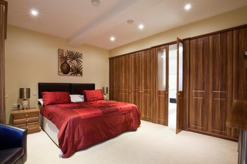 a bedroom with a red bed and wooden cabinets at Premier Apartments in Caister-on-Sea