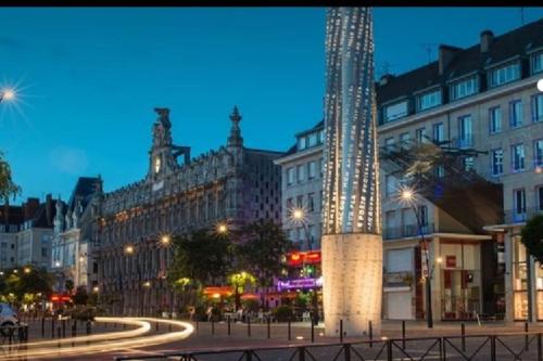 une rue de la ville avec une tour d'horloge la nuit dans l'établissement Fadil, à Valenciennes