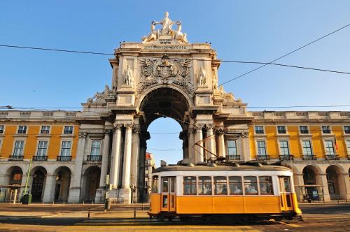 a yellow tram in front of a building at Pousada de Lisboa - Small Luxury Hotels Of The World in Lisbon