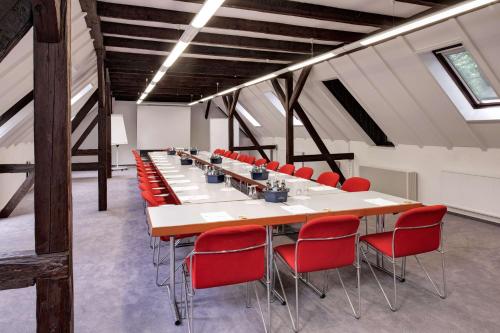 una sala de conferencias con una mesa larga y sillas rojas en Hotel Schloss Eckberg, en Dresden