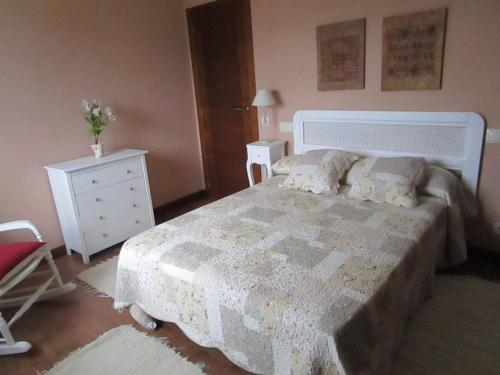 a bedroom with a bed and a chair and a dresser at La Cabadachan in Vilaboa