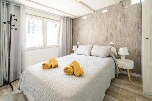 una camera da letto con un letto bianco e asciugamani gialli di Apartamento ALMA con terreno privado y parking compartido - a 800m de Playa Poniente a Benidorm