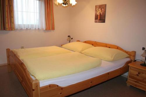 ein Schlafzimmer mit einem großen Holzbett mit weißer Bettwäsche in der Unterkunft Ferienwohnungen Foidlhof in Hochfilzen