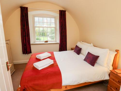 1 dormitorio con 1 cama con cortinas rojas y ventana en The Mill, en Buxton