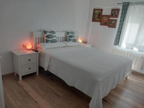 a white bedroom with a white bed and a night stand at Family apartment Andrea in Alaquas