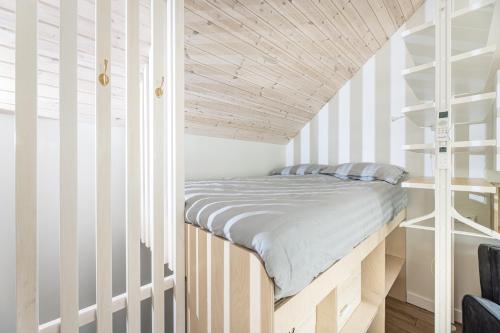 a bed in a room with a wooden ceiling at Apartamentai Čiki puki 2 aukštas in Palanga