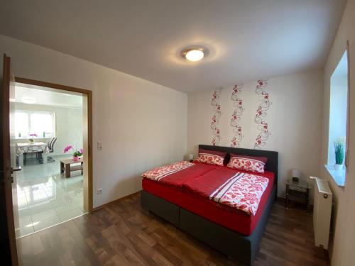 Schlafzimmer mit einem Bett mit einer roten Bettdecke in der Unterkunft Ferienwohnung Schardt in Annweiler am Trifels
