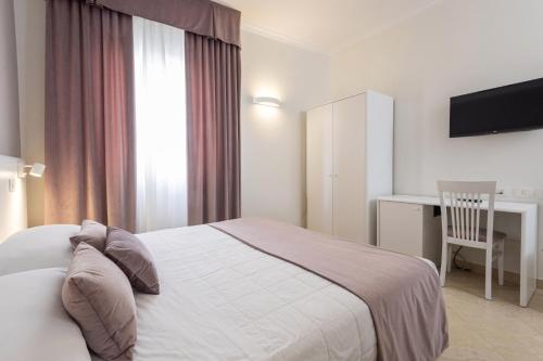 a bedroom with a bed and a desk and a chair at Hotel Centrale Spa & Relax in Alcamo