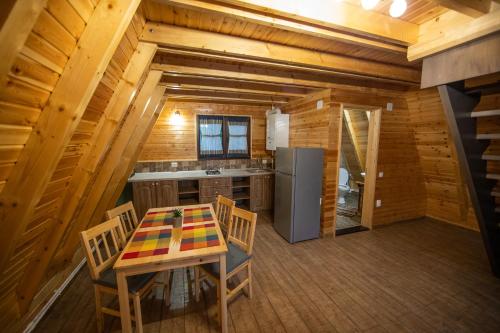 eine Küche mit einem Tisch und Stühlen in einer Hütte in der Unterkunft Catunul din Podei A-Frame in Dragoslavele