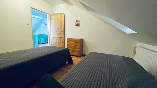 a attic bedroom with two beds and a window at Apartament Pod Kasztanami - ZIELONY in Ińsko