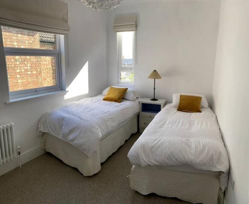 een slaapkamer met 2 bedden en een raam bij Distinctive Stamford townhouse in Lincolnshire