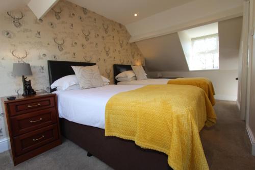 a bedroom with two beds with yellow blankets and a window at Fern Howe Guest House in Keswick