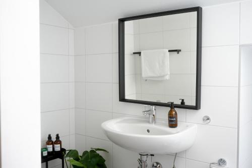 La salle de bains blanche est pourvue d'un lavabo et d'un miroir. dans l'établissement Exklusive Stadtoase mit Panoramablick nähe Hauptbahnhof, à Coblence