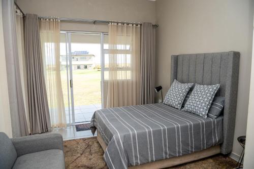 ein Schlafzimmer mit einem Bett, einem Sofa und einem Fenster in der Unterkunft 36 Emanzini Garden Units in Deneysville