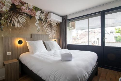 a bedroom with a large white bed with a window at O'Cub Hotel in Villeneuve-lès-Avignon