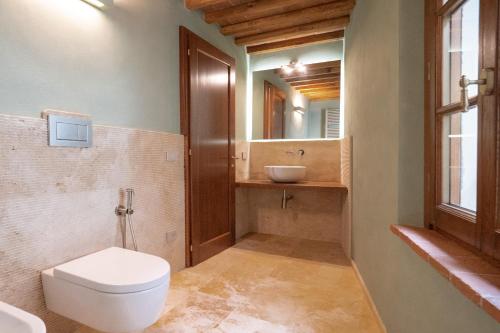 a bathroom with a toilet and a sink and a mirror at Delcorto Suites in Montepulciano