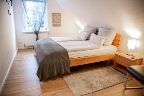 Schlafzimmer mit einem Bett mit weißer Bettwäsche und einem Fenster in der Unterkunft Apartment Auszeit in Isenbüttel