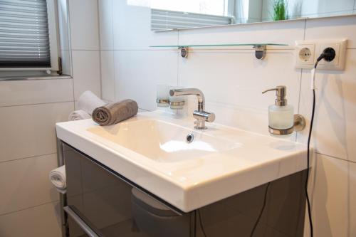 ein Badezimmer mit einem weißen Waschbecken und einem Spiegel in der Unterkunft Apartment Auszeit in Isenbüttel