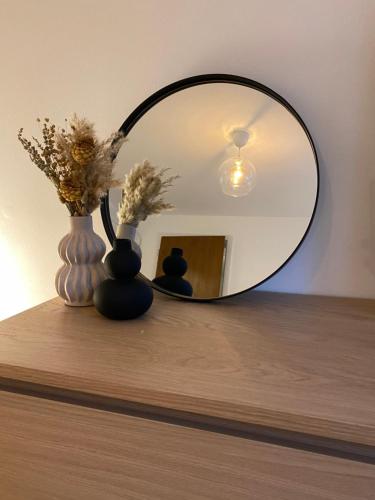 a mirror on top of a table with vases and flowers at Gemütliches Apartment am Waldrand in Haiterbach