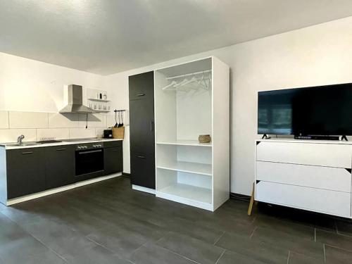 eine große weiße Küche mit einem großen TV an der Wand in der Unterkunft Gemütliche Wohnung in ruhigem Wohngebiet in Aschaffenburg
