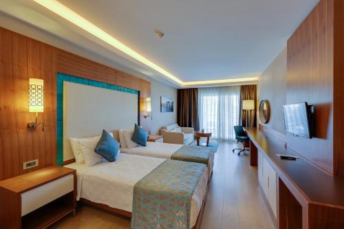 a hotel room with two beds and a couch at Ramada Hotel & Suites by Wyndham Kusadasi in Kusadası