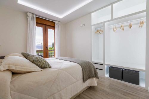 biała sypialnia z łóżkiem i oknem w obiekcie El balcón de Covelo w mieście Pontevedra