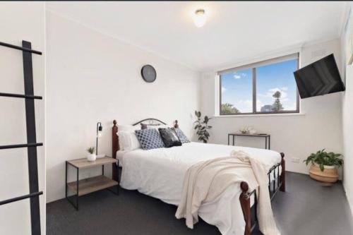 a white bedroom with a bed and a window at Beach-side Retreat in Frankston