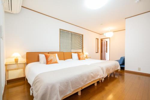 a bedroom with a large white bed with orange pillows at Hanamikaku貸切一軒家4LDK新小岩駅徒歩5分電車で東京駅13分新宿駅30分ディズニーまで30分成田エクスプレスで65分直通 in Tokyo