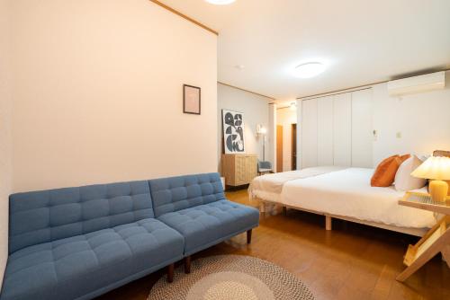 HANAMIKAKU-shinjuku/akihabara/asakusa/ginza/tokyo/narita/haneta Japanese House 100㎡ في طوكيو: غرفة نوم بها أريكة زرقاء وسرير