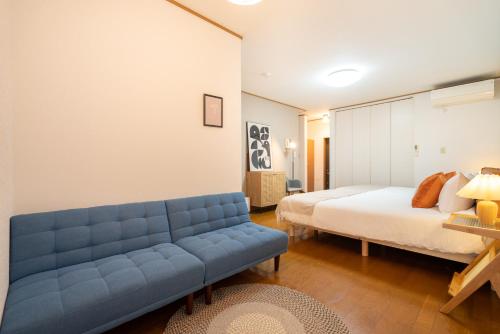 a bedroom with a blue couch and a bed at Hanamikaku貸切一軒家4LDK新小岩駅徒歩5分電車で東京駅13分新宿駅30分ディズニーまで30分成田エクスプレスで65分直通 in Tokyo