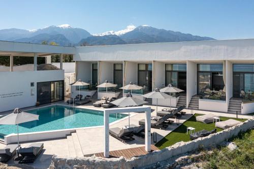 ein Hotel mit Pool und Bergen im Hintergrund in der Unterkunft Akrotiri Olympus Luxury Suites - Adults Only in Plaka