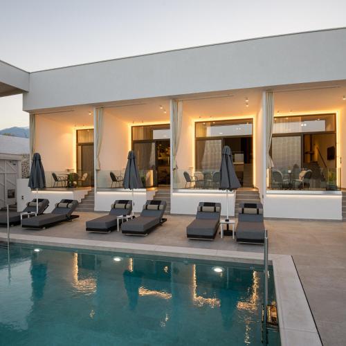 a house with a swimming pool and lounge chairs at Akrotiri Olympus Luxury Suites - Adults Only in Plaka Litochorou